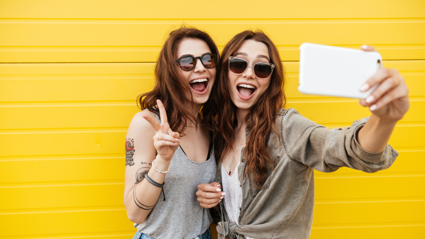 Two Girls Taking a Selfie with a Yellow Brick Wall Background